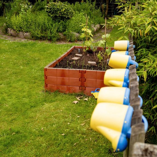 Garten mit Hochbeet und vielen Kinder-Gießkannen am Zaun
